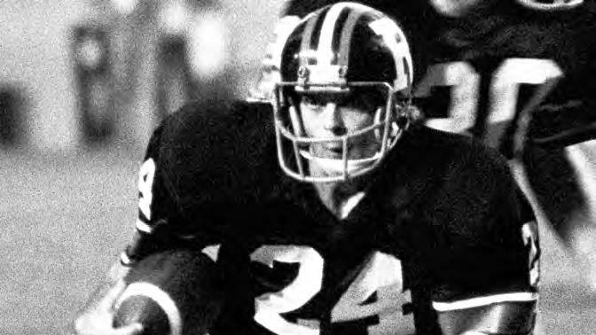 Ross Clarkson holds a football in full uniform on the field.